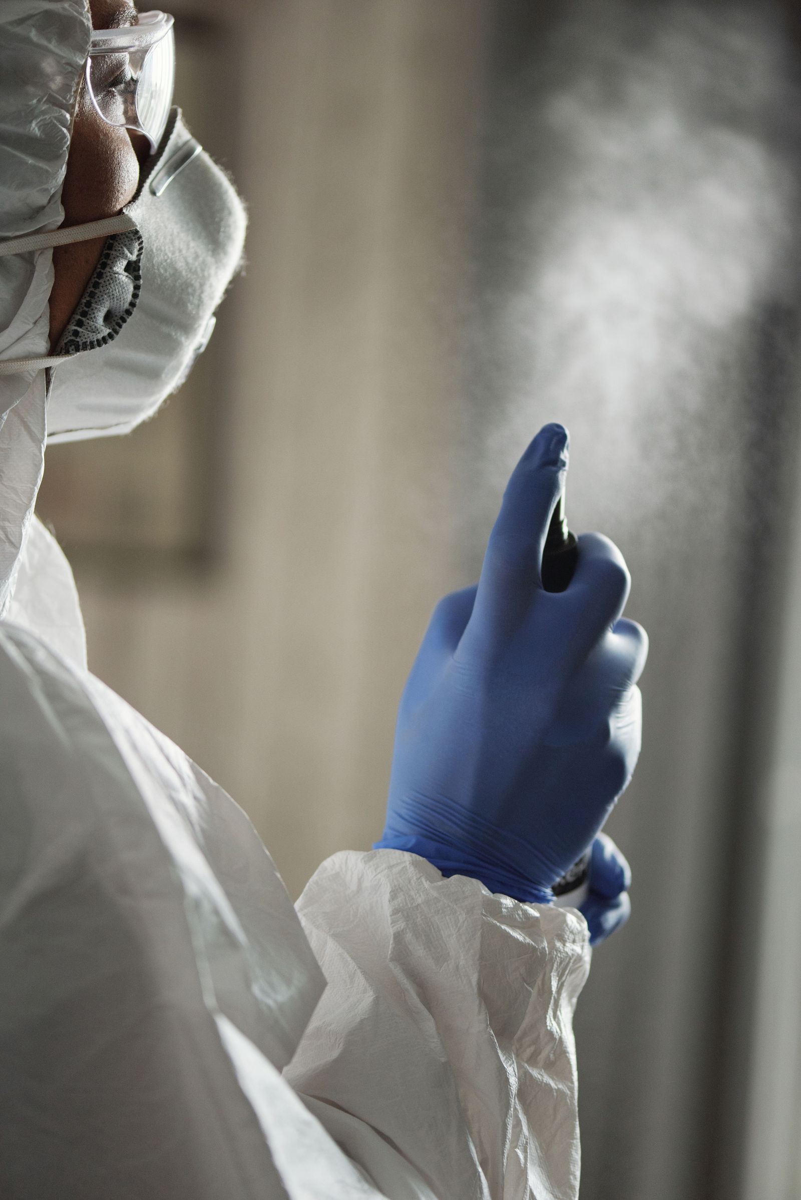 Technicien en combinaison réalisant une désinfection